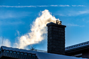 Gęsty dym wydobywa się z komina kotłowni mieszkalnego w mieście. © FotoDax