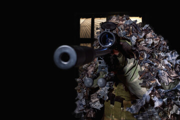 A soldier in camouflage fires a weapon on a black background