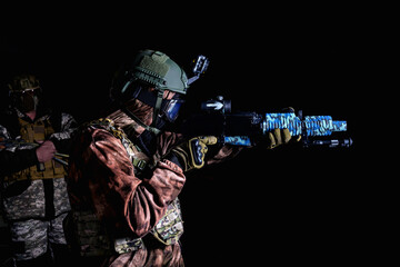 A soldier in camouflage fires a weapon on a black background