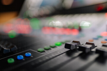 Close-up view of a professional audio mixing console with colorful buttons and sliders, showcasing intricate details of sound engineering and music production equipment