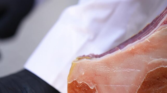 Close-up of a long knife slicing bacon. A long knife is used to slice jamon into thin slices. A long knife is used to slice bacon into thin slices.