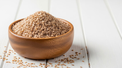 Wooden bowl filled with dry oats on a white wooden surface.