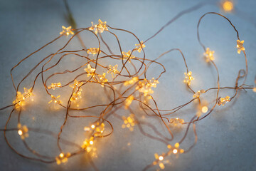 Warm yellow star-shaped fairy lights on copper wire creating soft bokeh on a blue background.