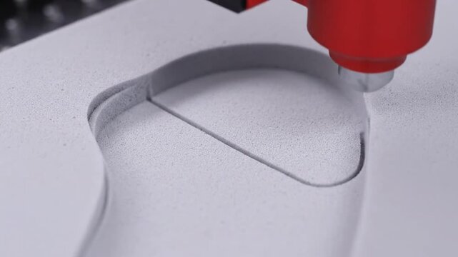 Automated Milling Machine Carving a Gray Material with a Red Milling Head Creating Detailed Smooth Curves