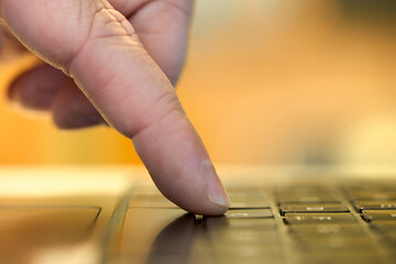 Finger pressing key on laptop keyboard