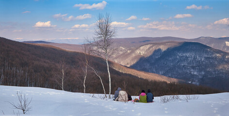 A group of tourists admire the winter landscape from the top of a mountain. Active recreation in the snow-covered mountains