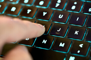 Finger pressing key on dark keyboard