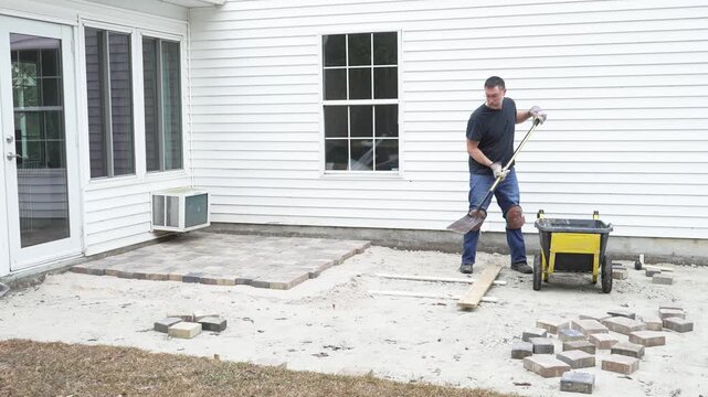 Man working on his home DIY project building a paver patio in his back yard