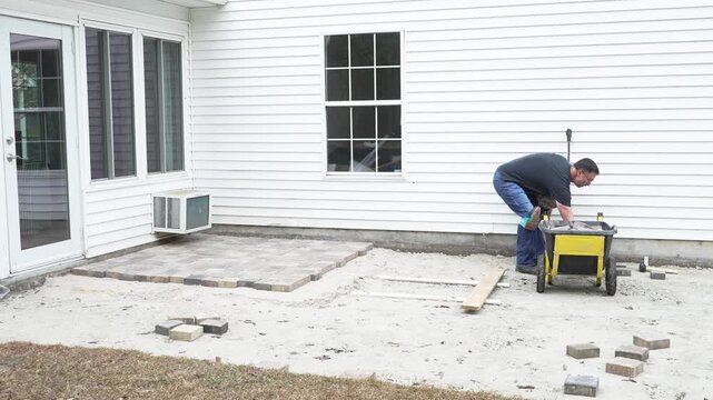 Man working on his home DIY project building a paver patio in his back yard