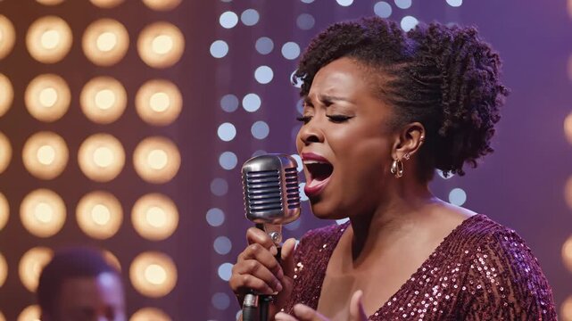 Close-up of a passionate Black female singer performing on stage. A woman sings a soulful song into a retro microphone at a live music concert