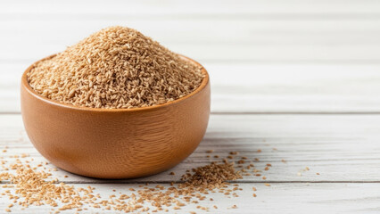 Ground sesame seeds in a wooden bowl on a white wooden surface.