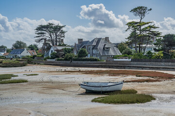 Boat in a bay during low tide with houses in background in Côtes-d'Armor, Brittany France