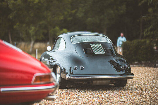 Classic black sports car coupe with a red Porsche 911 in the foreground