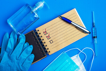 Hand sanitizer face mask and checklist concept with medical supplies on blue background