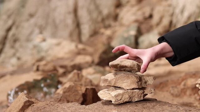 A woman stacks stones one on top of the other, making a wish. Stacking stones into a tower in a cave. Prohodna Cave, popular names &mdash; Eyes of God or Devil&rsquo;s Eyes. Bulgaria