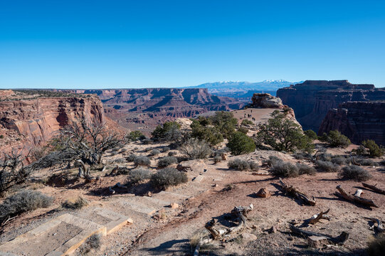 Tourists on Shafer Canyon Overlook in Canyonlands National Park, Utah on clear sunny winter afternoon.