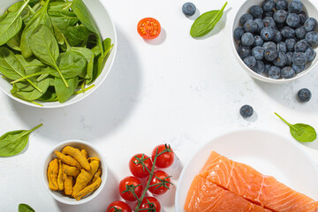 Healthy anti inflammatory diet food ingredients white background salmon blueberry spinach copy space