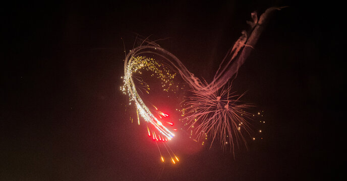 Colorful blur of lights paints the night as a Ferris wheel spins. With a slow shutter speed, red, yellow, and green streaks blend, creating a mesmerizing display of vibrant hues in motion