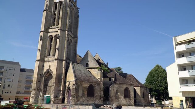 The Saint-Medard church a, large Gothic style church standing against a blue sky, Creil, Oise, France.