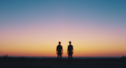 Fototapeta premium Two people standing on a field at sunset