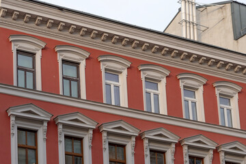 Fototapeta premium red facade of a historic residential building with classic windows and stucco molding in a European city
