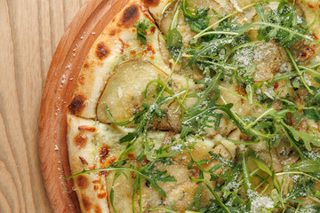 Delicious flatbread with potatoes, green herbs, and cheese served on a wooden board