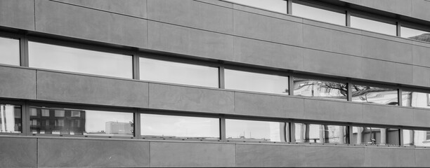 Modern building exterior showcasing sleek architectural design with reflective windows revealing city elements. Ideal for business and architectural content.