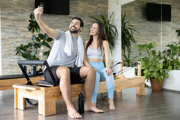 Obraz premium Man and woman share a light-hearted selfie at the pilates studio, creating a joyful atmosphere of fitness connection.