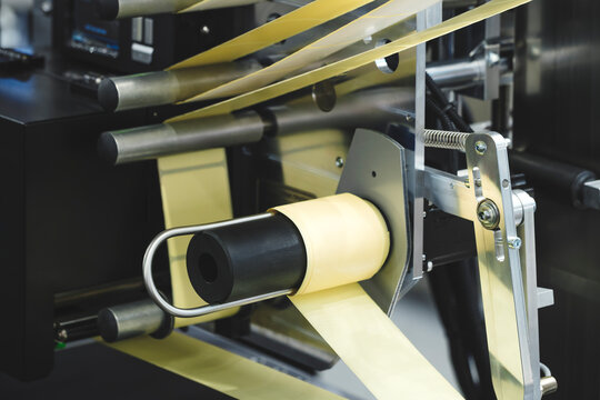 Paper sticker tape for sticking on food packaging on stickering machine of packaging container in factory or plant. Industrial concept background