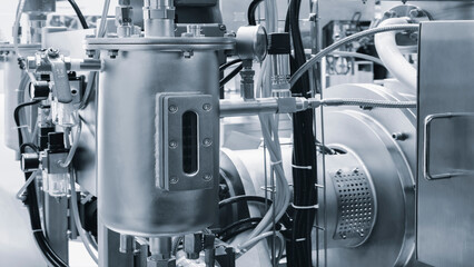 Large industrial machine in pharmaceutical factory with many stainless steel pipes, taps and other...