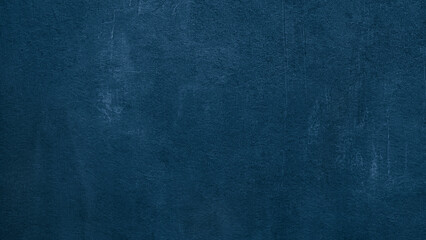 wall in a rich blue hue with a rough, uneven texture as background. It is made of concrete or another material textured to create a unique, visually interesting surface.