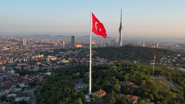 Drone footage showing a large Turkish flag on Camlica Hill with Camlica Tower and the vast Istanbul skyline in clear daylight.