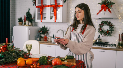 Young woman preparing healthy Christmas dinner in a festive kitchen with decorations