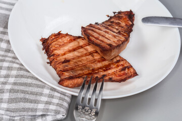 Grilled turkey steaks on a white dish close-up