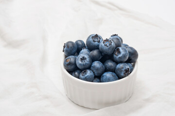 A bowl of ripe blueberries on a white background.