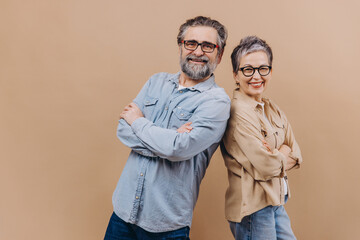 Happy senior couple standing back to back smiling