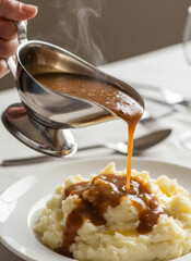 Steam Rising Gravy Is Poured Over Mashed Potatoes In A Silver Gravy Boat At Dinner Table