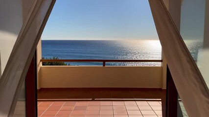 White sheer curtains blowing gently in the breeze to reveal a sparkling blue ocean horizon from a sunny balcony, ideal for luxury travel and summer relaxation concepts