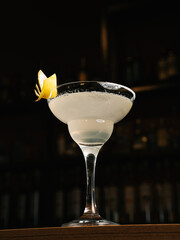 Margarita cocktail with lemon twist on dark bar counter