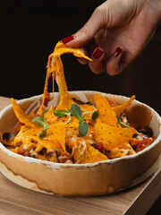 Loaded nachos with melted cheese and hand picking chip