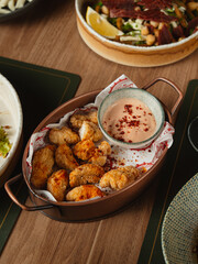 Fried bites with creamy dipping sauce on rustic wooden table