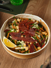 Rustic salad with croutons chickpeas and cured meat in ceramic bowl