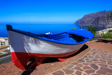 Boat at viewpoint Mirador Archipenque in front of vertical cliffs of the Giants (Acantilados de Los Gigantes) and Atlantic Ocean at Canary Island Tenerife, Spain