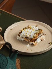 Layered pastry dessert with cream and pistachio on rustic plate