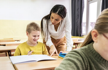The students are taking an exam in the classroom, focused on their papers. The teacher walks around the room, quietly checking on their progress.	
