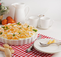Tangerine cake in baking ceramic dish on red napkin, copy space