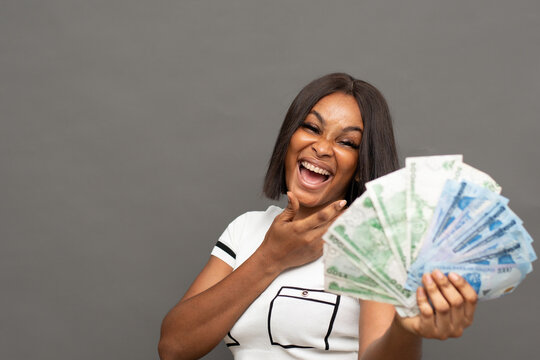 A happy young nigerian woman showing some new naira notes.