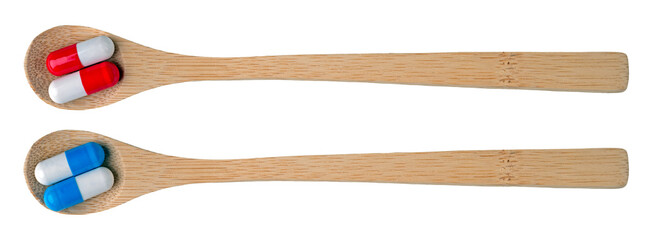 Wooden spoon and colorful capsules arranged two to a spoon. Isolated background.