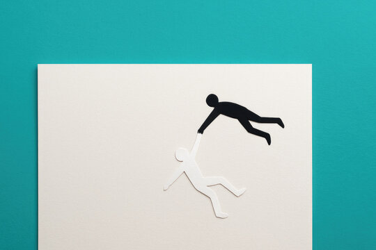 Silhouettes of people, one saving the other, support and help. Space for text.