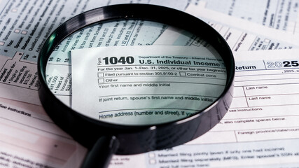 Important U.S. tax form and magnifying glass on paperwork for 2025 tax season preparation and review